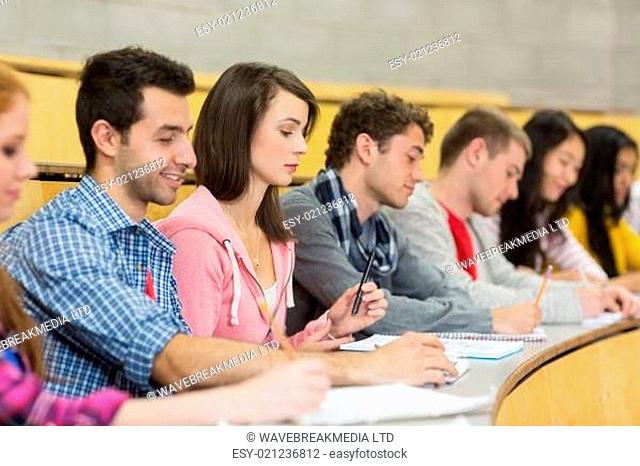 Students writing notes in a row at the lecture hall