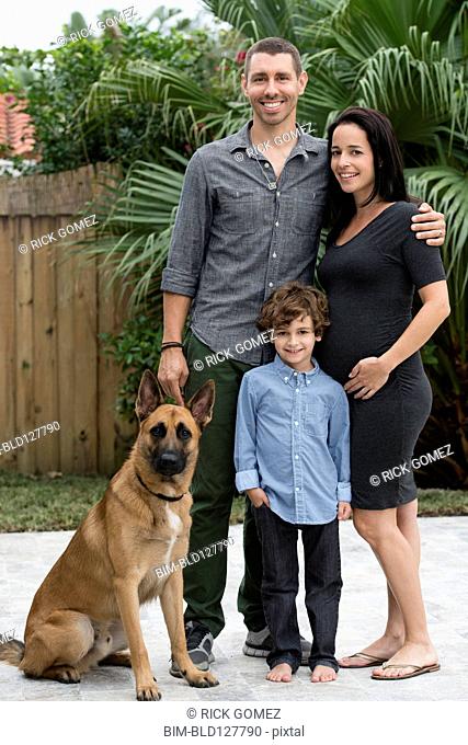 Family smiling together with dog outdoors
