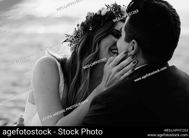 Happy bridal couple kissing each other at the beach, black and white