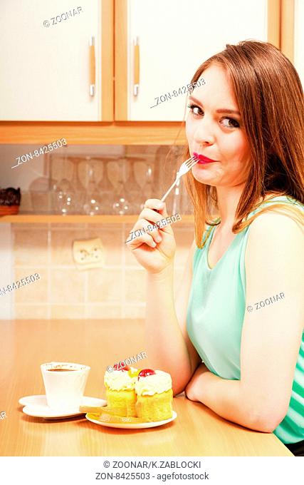 Woman with coffee eating cream cake. Gluttony