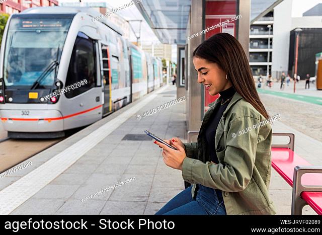 Woman using mobile phone at tram station