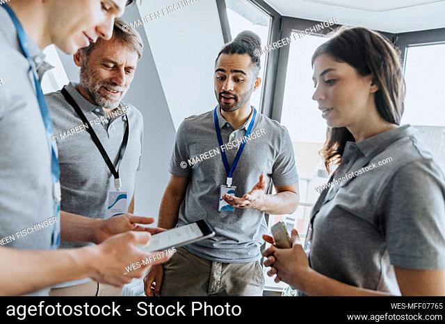 Male professional discussing over digital tablet with colleagues during conference