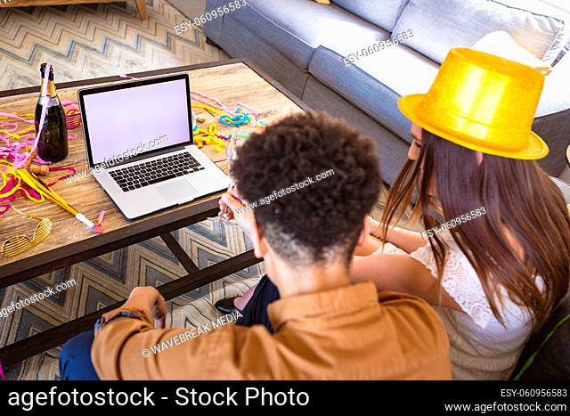 Biracial couple enjoying virtual party through video call on laptop with copy space