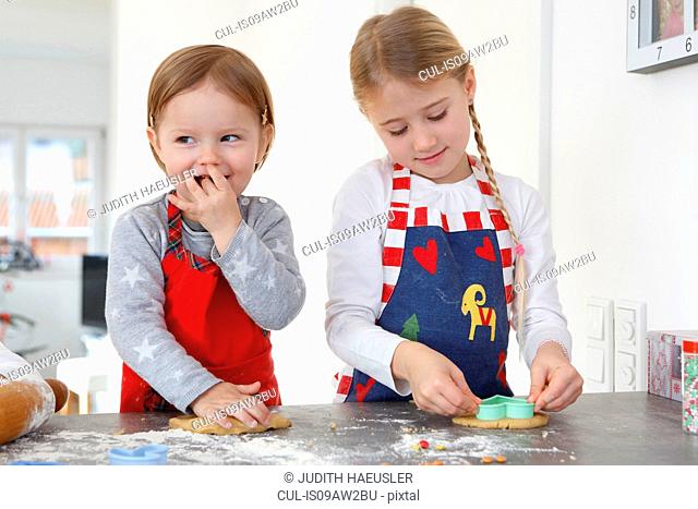 Girls at kitchen counter making cookies smiling