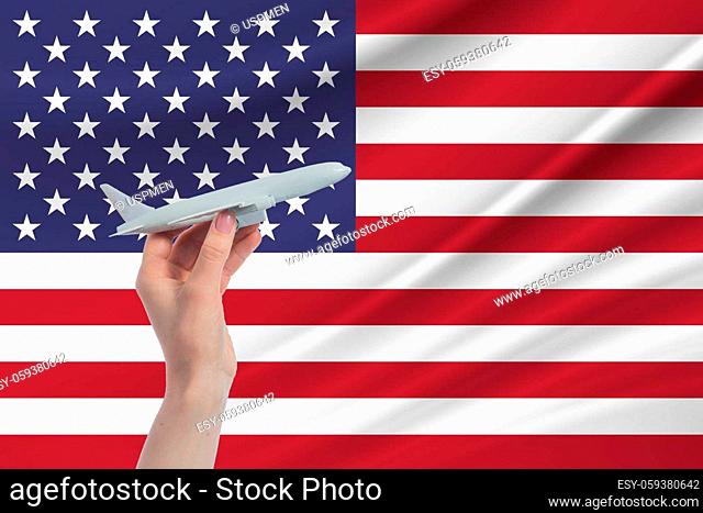 Airplane in hand with national flag of United States. Travel to United States
