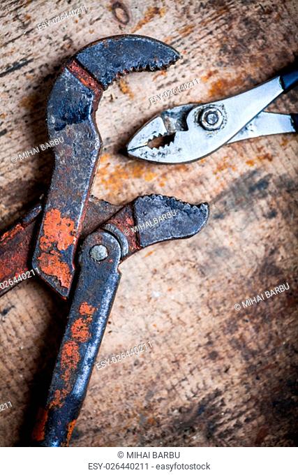 Color image of an adjustable wrench and some pliers on a wooden plank