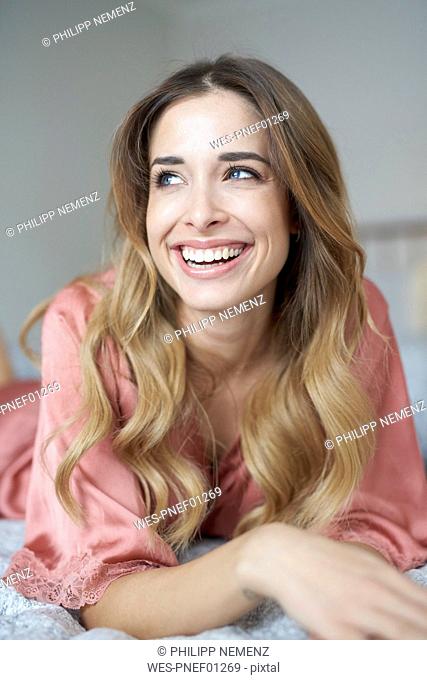 Laughing young woman in dressing gown lying in bed
