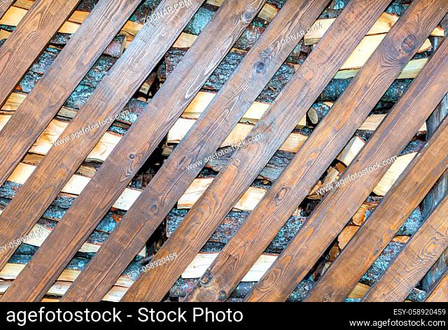 Chopped and stacked up dry firewood with diagonal boards as background texture
