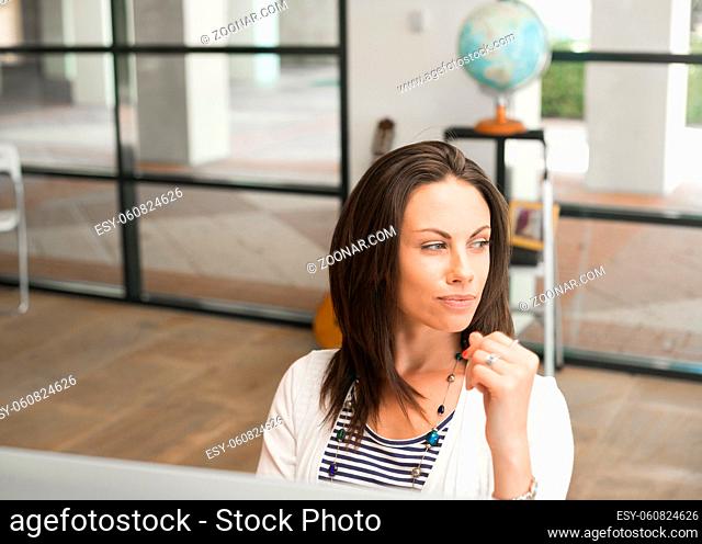 Young attractive brunette woman sitting at desk and looking away
