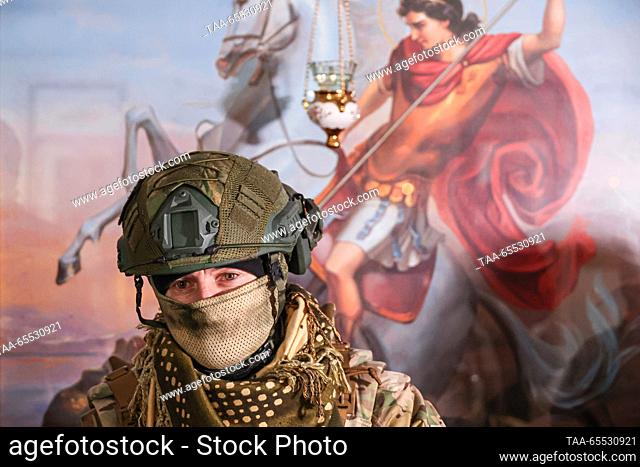 RUSSIA, ZAPOROZHYE REGION - NOVEMBER 27, 2023: A serviceman is seen in front of an icon of St George the Victory Bearer during a prayer service led by chaplain...