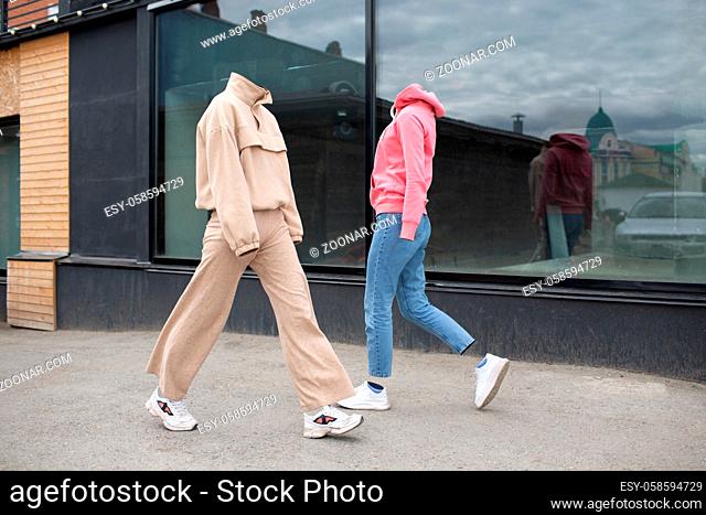 Empty woman clothes walk on street wearing hoody, jeans trousers, sneakers and colorful trainers