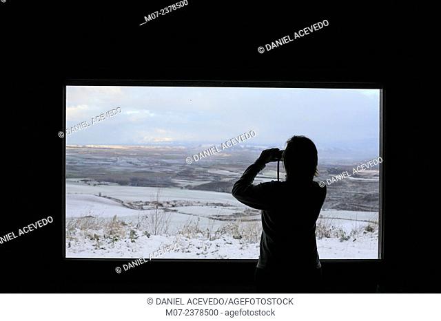 Woman taking winter landscape pictures with ther smartphone from her living room. Rioja wine region, Spain