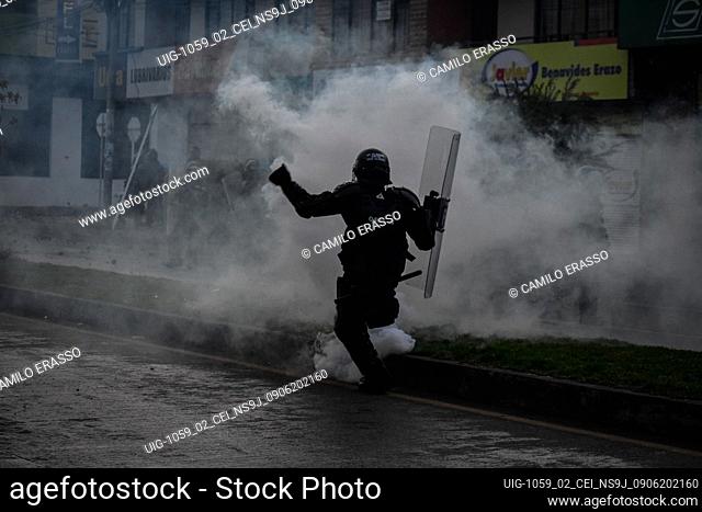 A Colombia's riot police officer kicks back a tear gas canister during clashes as demonstrations escalate to unrest and clashes between demonstrators and...