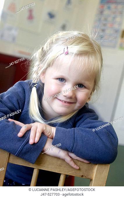 3 year old girl smiling into camera at nursery