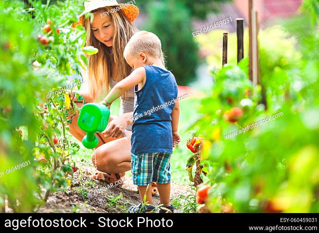 Cute toddler helphing out mom in the garden