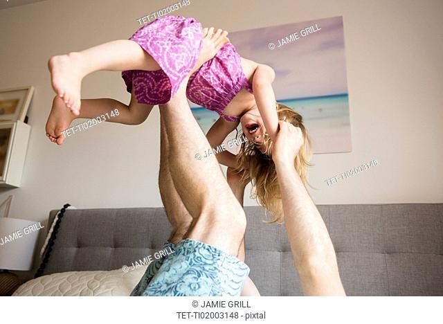 Father lifting daughter (2-3) with legs