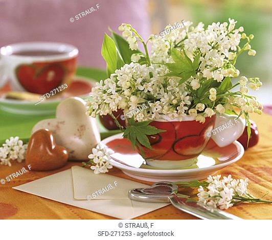 White lilac and lilies-of-the valley in cup with heart motifs