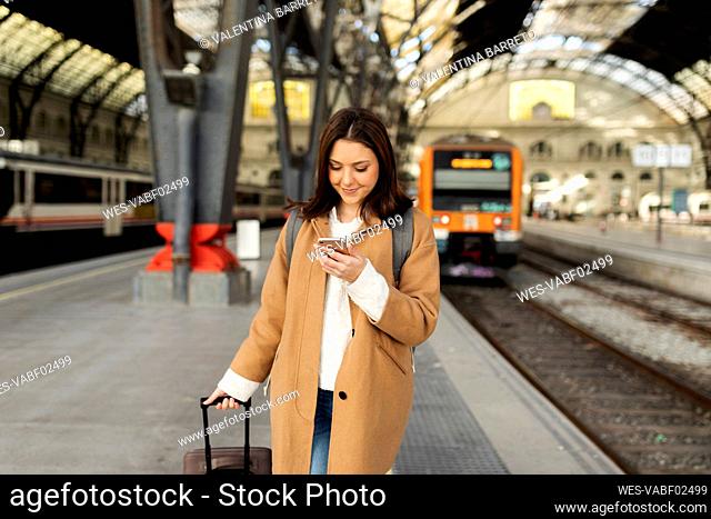 Young woman using cell phone at the train station