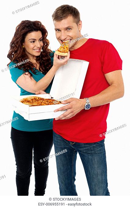 Caring girlfriend making her boyfriend eat pizza. Adorable love couple