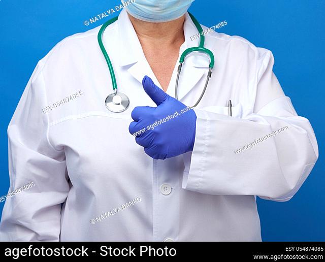 woman in white coat, wearing blue medical latex gloves on her hands, showing like gesture, approval concept