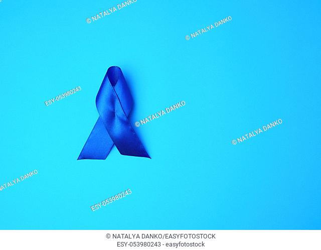 Dark blue awareness ribbon on blue background. concept of timely research and disease prevention colon malignancies, chronic fatigue syndrome