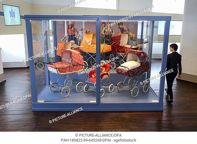 21 August 2018, Germany, Zeitz: A woman looks into a new showcase with Zekwia prams from the 1970s. Under the title ""The Zekiwa Years""