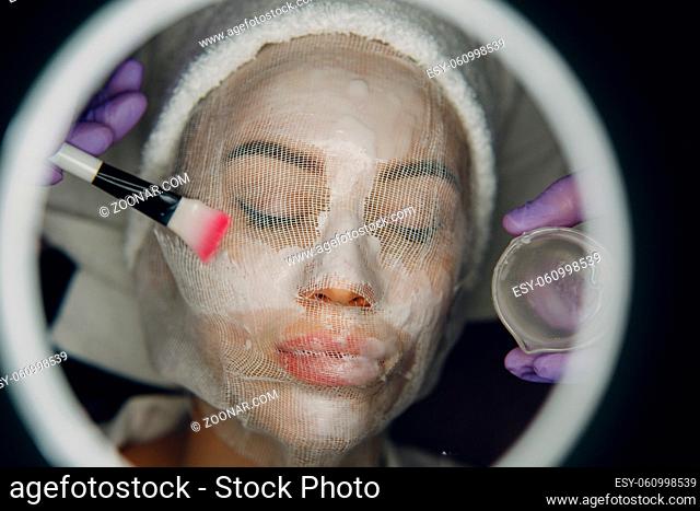 Paraffin Face Mask gauze bandage Therapy Young Woman Receiving Facial Skin Care Treatment. Beautician Pouring Wax Applying