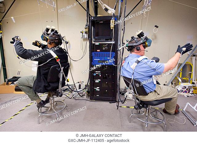 NASA astronauts Alvin Drew (left) and Steve Bowen, both STS-133 mission specialists, use virtual reality hardware in the Space Vehicle Mock-up Facility at...