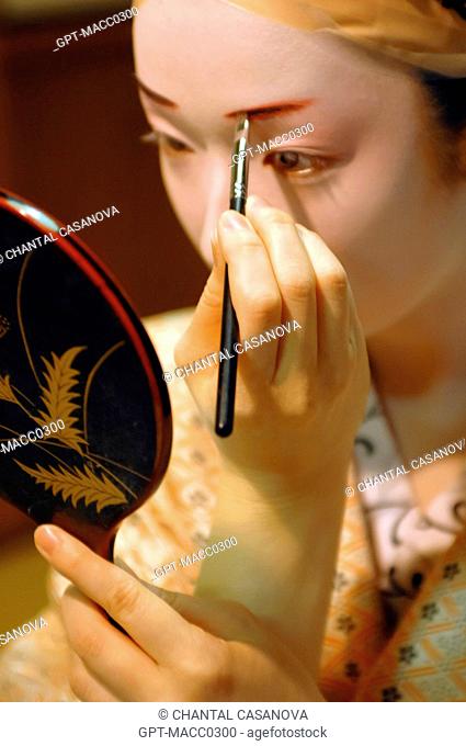 A GEIKO’S GEISHA TRADITIONAL MAKEUP DORAN, DRAWING THE EYEBROWS WITH RED AND BLACK MAKEUP, THE HAIR IS TIED BACK TO GO UNDER A WIG KATSURA, GION DISTRICT, KYOTO