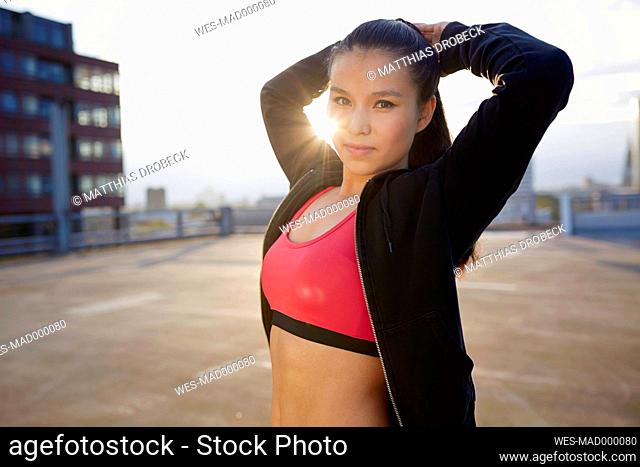 Portrait of young female Asian sportswoman doing stretching exercises