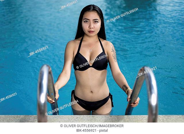 Asian young woman is climbing out of a swimming pool