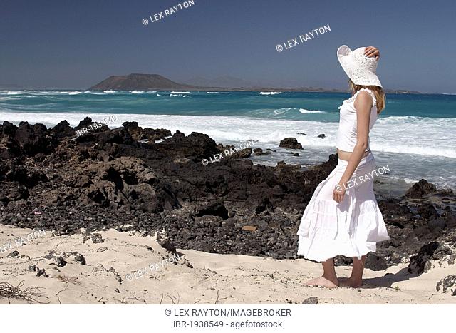 Woman on a rocky beach, Corralejo, Fuerteventura, Lanzarote in the back, Canary Islands, Spain, Europe