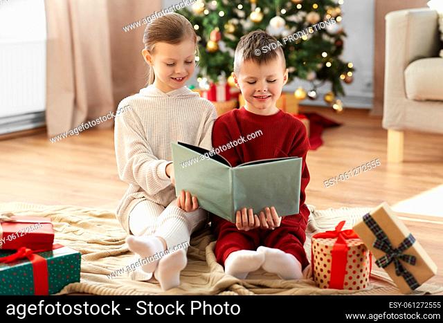 happy children reading book on christmas at home