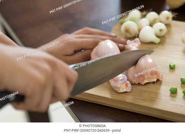 Woman chopping meat on a cutting board