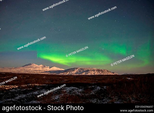 Colorful northern lights above snow-covered mountains in Iceland