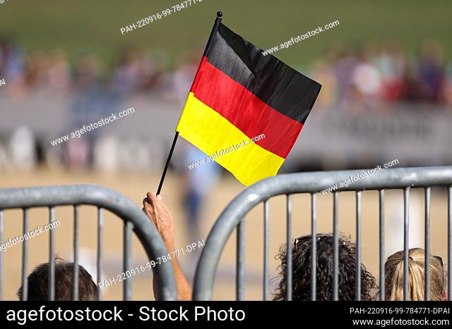 16 September 2022, Italy, Rocca Di Papa: Equestrian sport: World Championship, Eventing, Dressage. A fan waves a German flag during the ride of the rider...