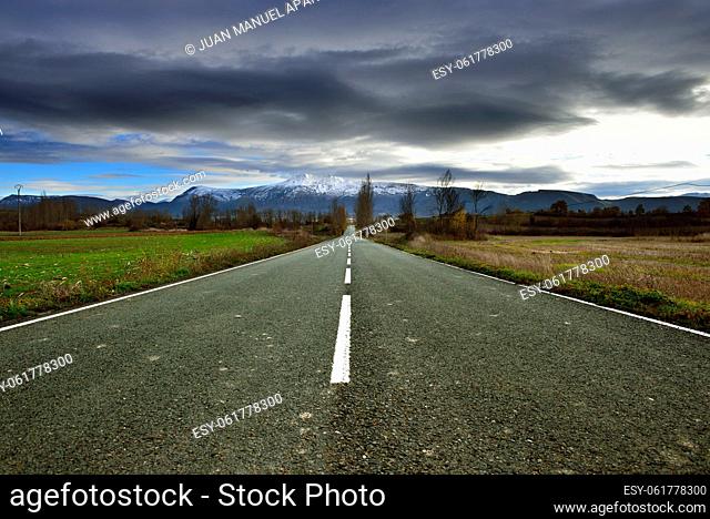Road and snow mountains in the background in the Tobalina Valley, Burgos, Spain