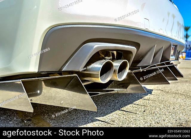 Close up of a dual exhaust pipe on a white car with tail spikes. Custom cars in Southern California summer 2017