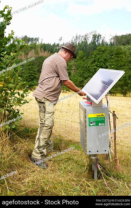24 July 2023, Rhineland-Palatinate, Hundsdorf: Sheep farmer and wolf officer Werner Neumann switches on the electric fence that is supposed to protect his flock...