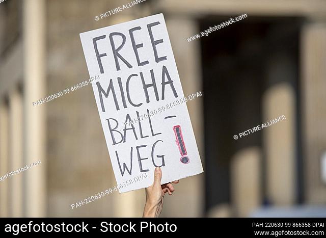 30 June 2022, Berlin: A woman holds a placard reading ""Free Micha Ball-weg!"" at a rally in front of the Brandenburg Gate after the arrest of ""Querdenken""...