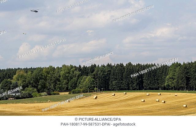 17 August 2018, Germany, Geyer: A helicopter flies with a Supracon probe over the Ore Mountains. Researchers from Freiberg hope to use the magnetic field...