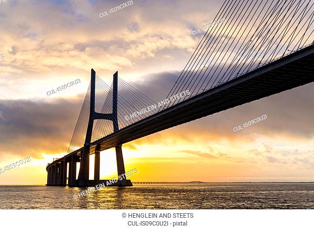 Vasco da Gama Bridge spanning Tagus river at sunset, Portugal