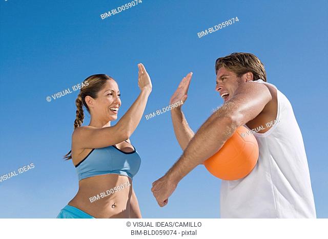Hispanic couple with volleyball high-fiving