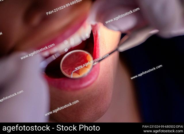 23 October 2023, North Rhine-Westphalia, Mönchengladbach: Dentist Dr. Kranz uses a mirror to look at a patient's teeth in his dental practice