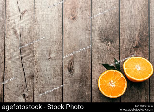Sliced halves of orange fruit on gray wooden background. Pulp and green leaves. High quality photo