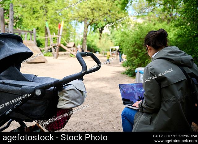 ILLUSTRATION - 04 May 2023, Berlin: A mother sits at her laptop while sitting next to her stroller in the playground.(to dpa ""Morally on the hook"" - 100 years...