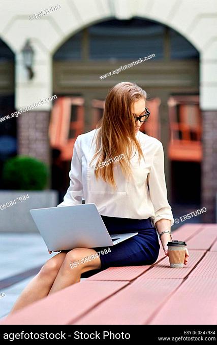 Young business woman in glasses working at laptop outdoors. woman enjoy her work