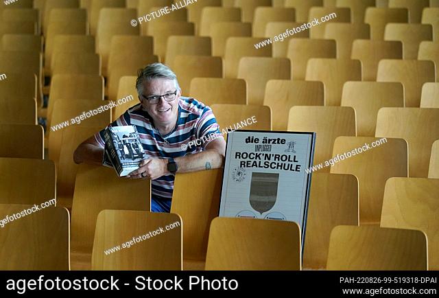 PRODUCTION - 07 July 2022, Hamburg: Janitor André Schulz sits in the auditorium of the Albert Schweitzer High School next to the platinum award for the...