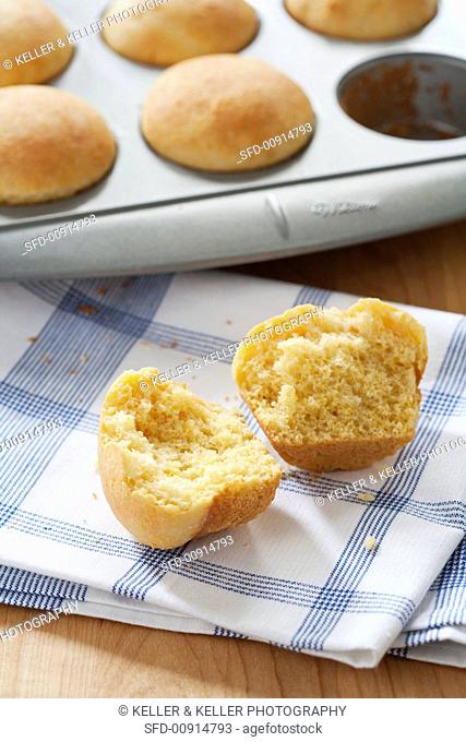 Corn Muffin Halved on a Dish Towel; Muffins in Baking Tin