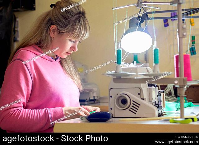 Girl engaged in needlework at a desk with a sewing machine